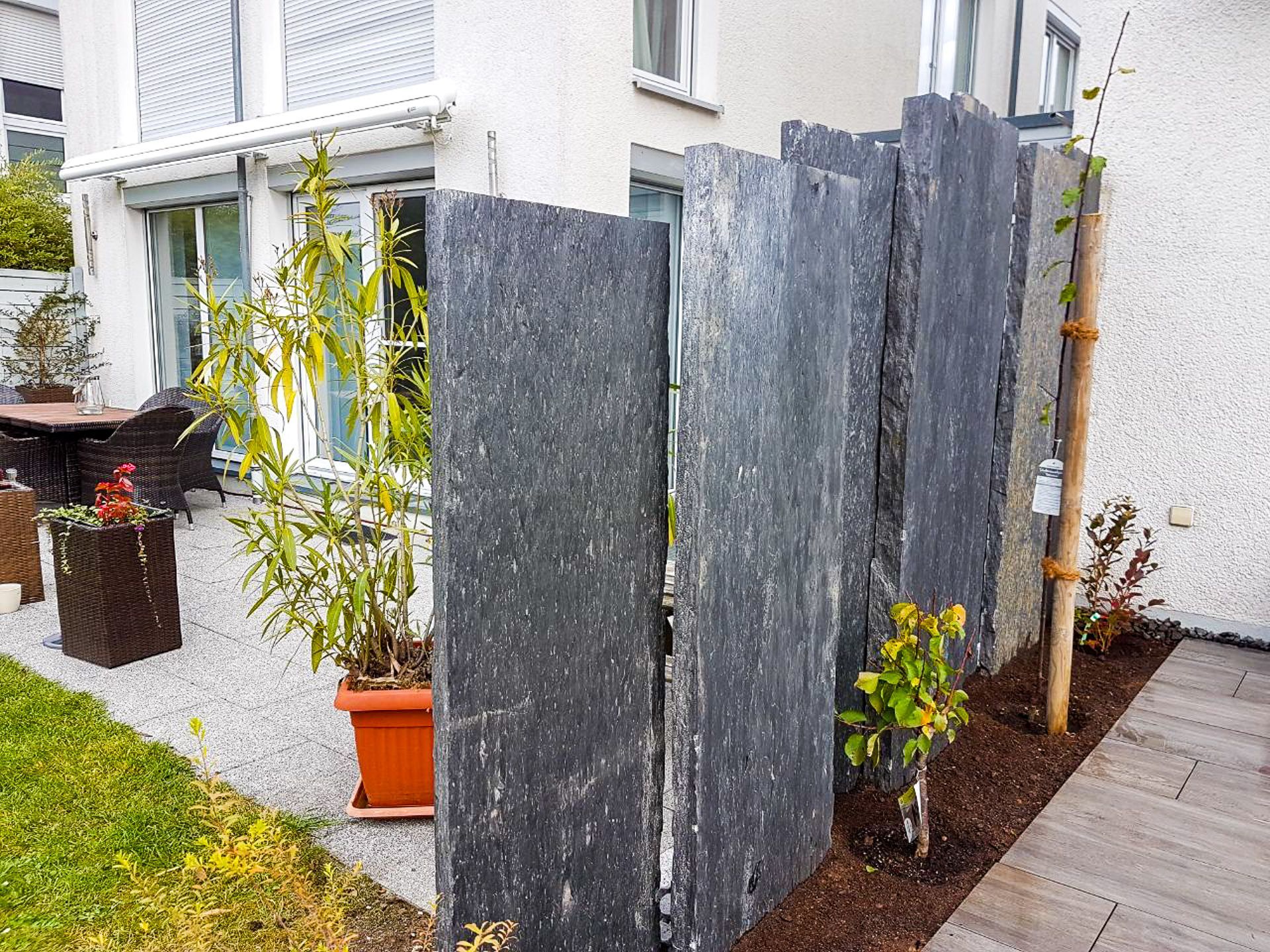 Ein Steinzaun umgibt eine Terrasse vor einem Haus.