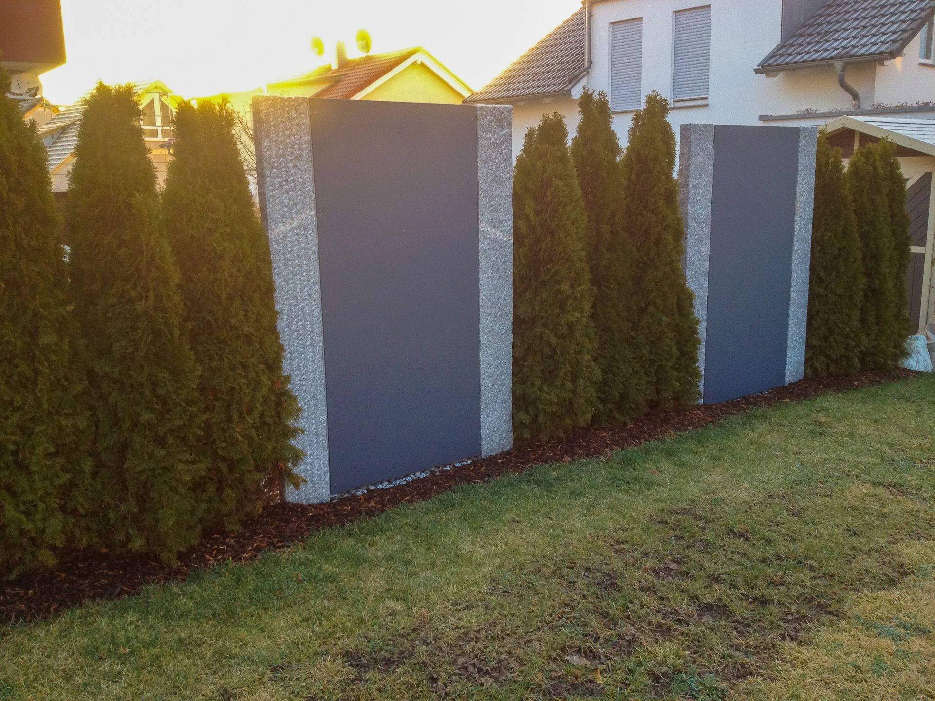 Ein Zaun mit Bäumen und einem Haus im Hintergrund