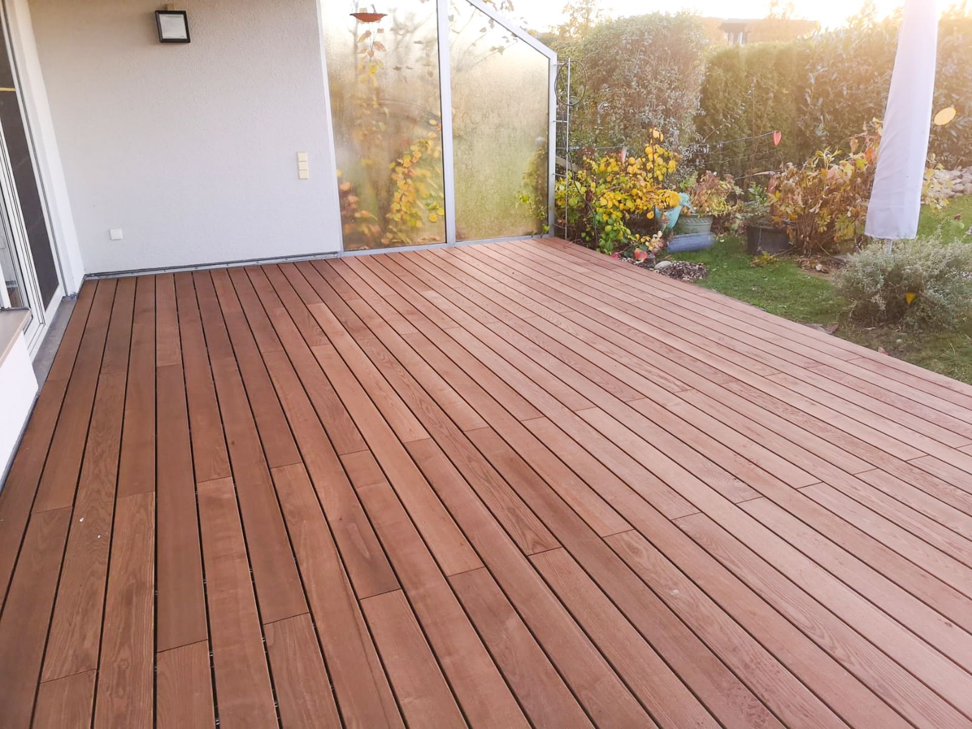 Ein Holzdeck mit einem Glaszaun im Hintergrund.