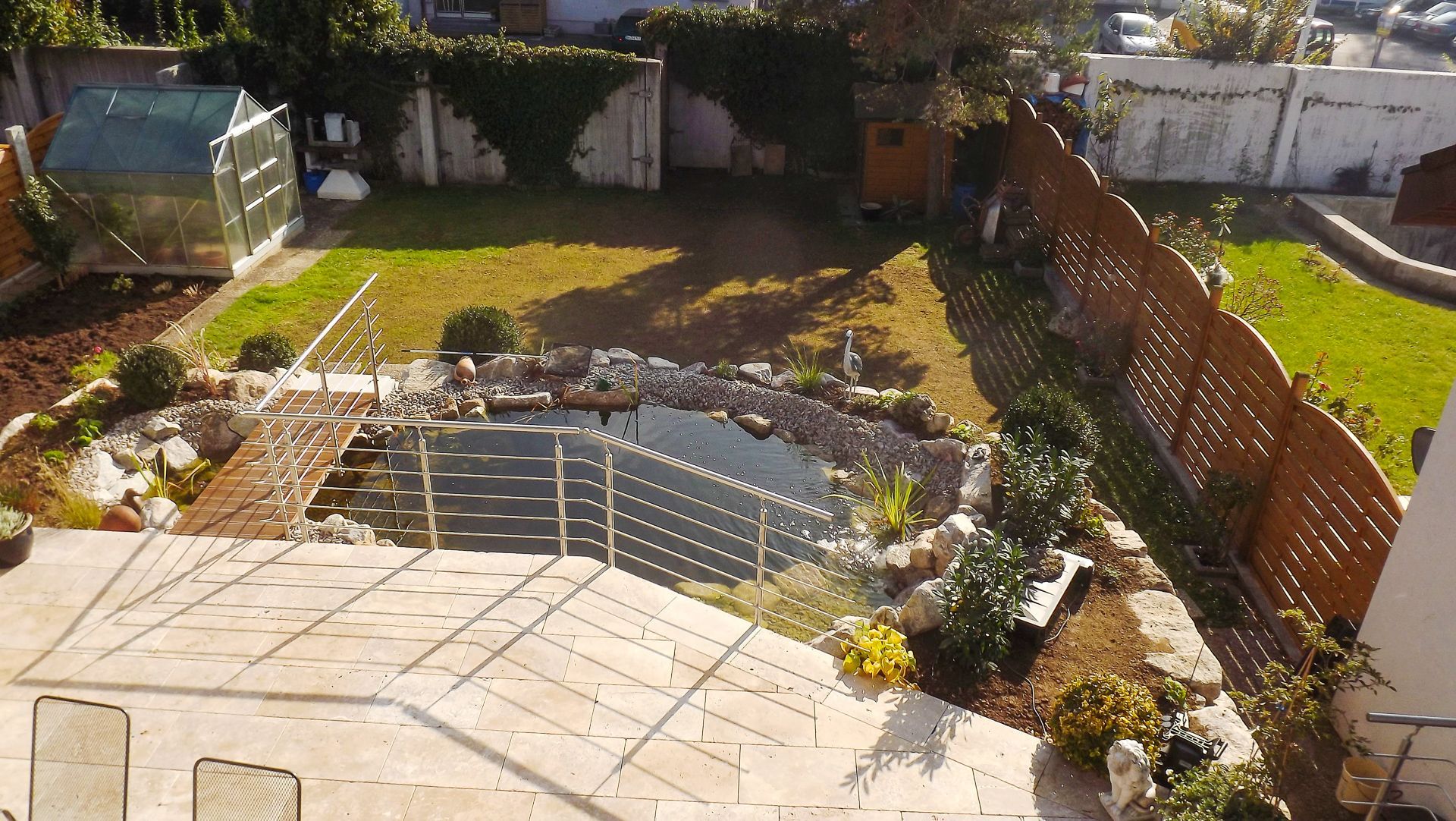 Eine Luftaufnahme eines Hinterhofs mit einem Teich und einem Gewächshaus