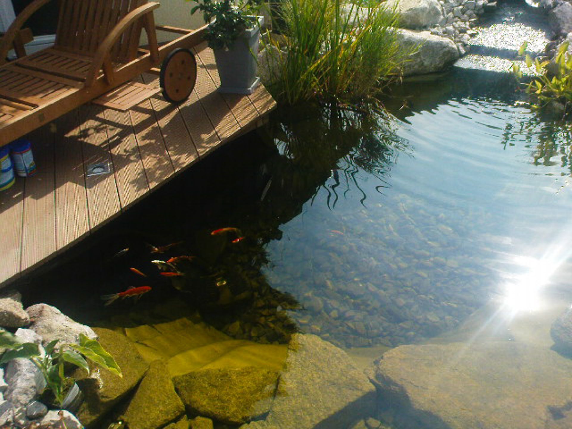 Ein Stuhl steht auf einem Holzdeck neben einem Teich