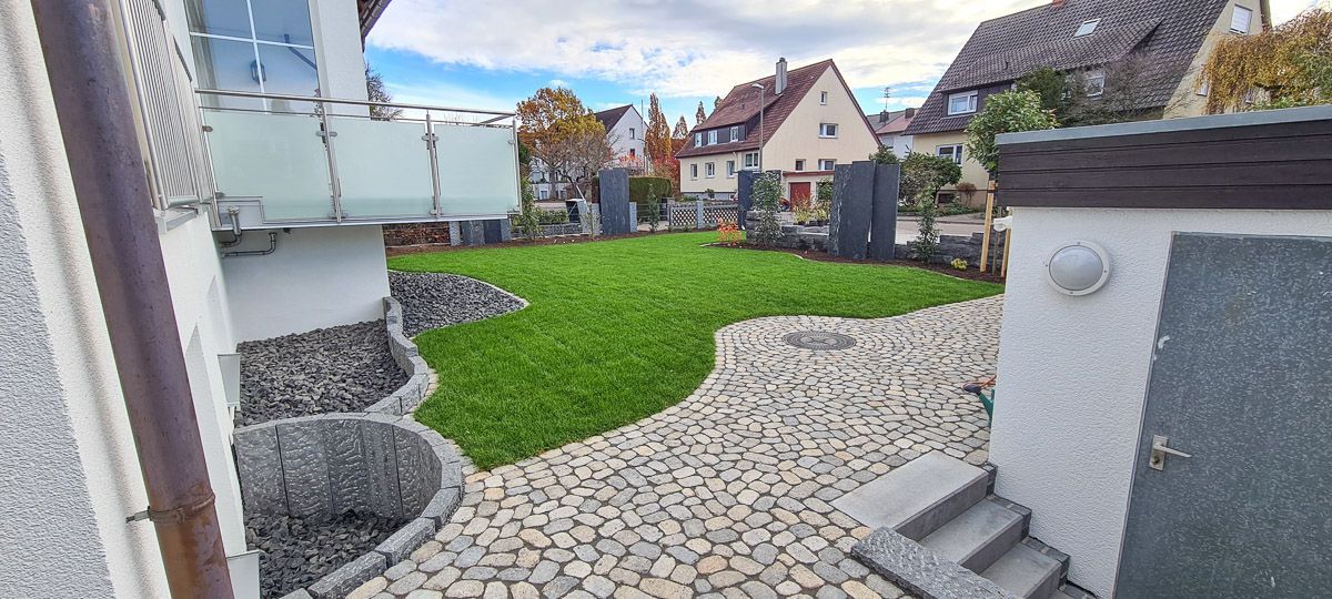 Ein Haus mit einer großen Rasenfläche davor und einem Steinweg, der dorthin führt.