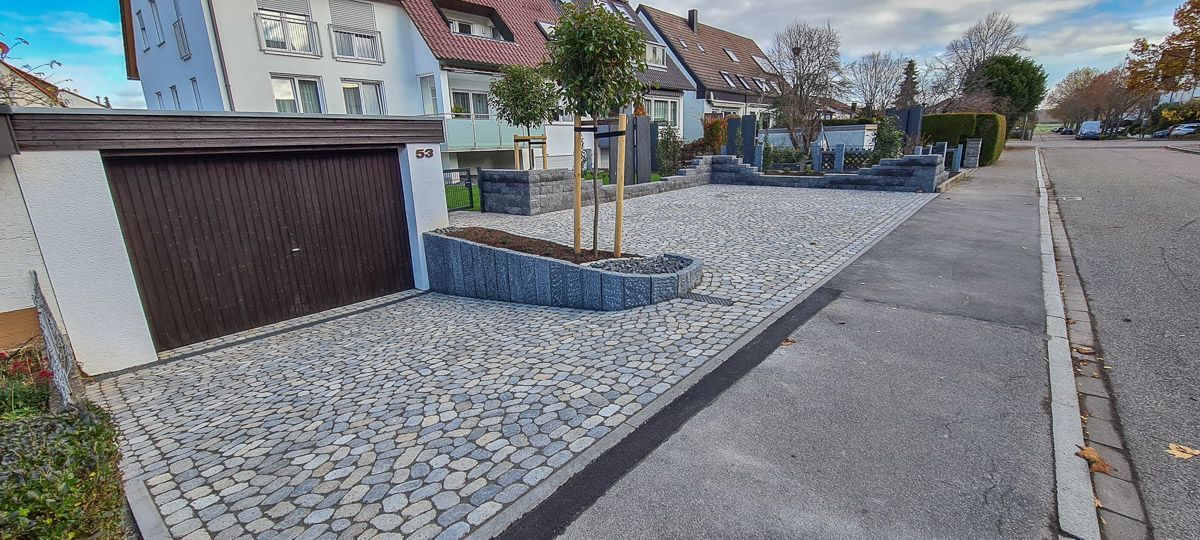 Eine Einfahrt mit einer Garage und einem Baum in der Mitte.