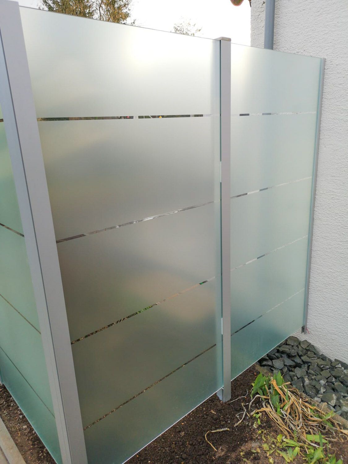 Neben einem Haus steht ein Zaun aus Milchglas.