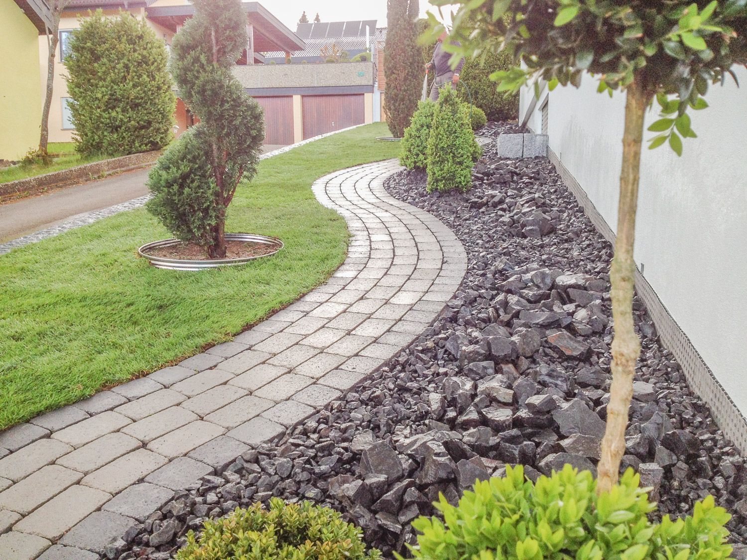 Ein Ziegelweg führt zu einem Haus, das von Felsen und Gras umgeben ist.