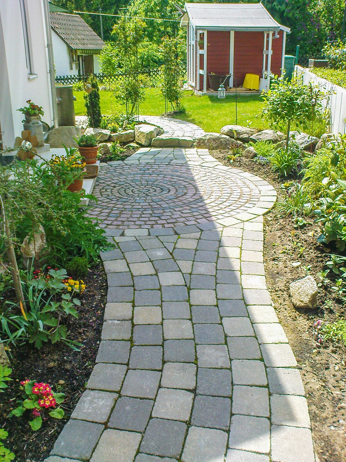 Ein Ziegelweg führt zu einem roten Schuppen im Hinterhof