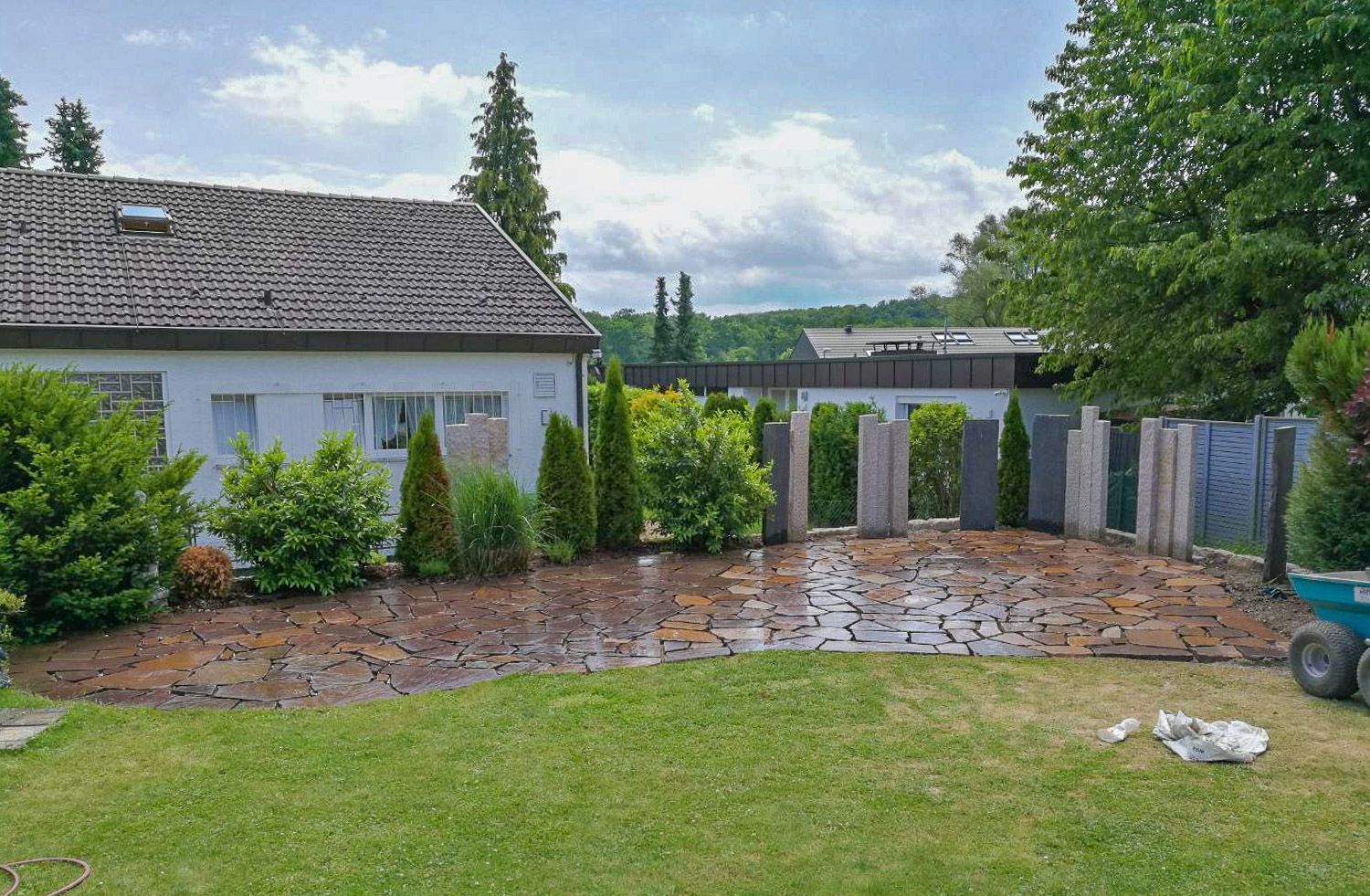 Ein Haus mit einer gepflasterten Auffahrt und einer Schubkarre davor.