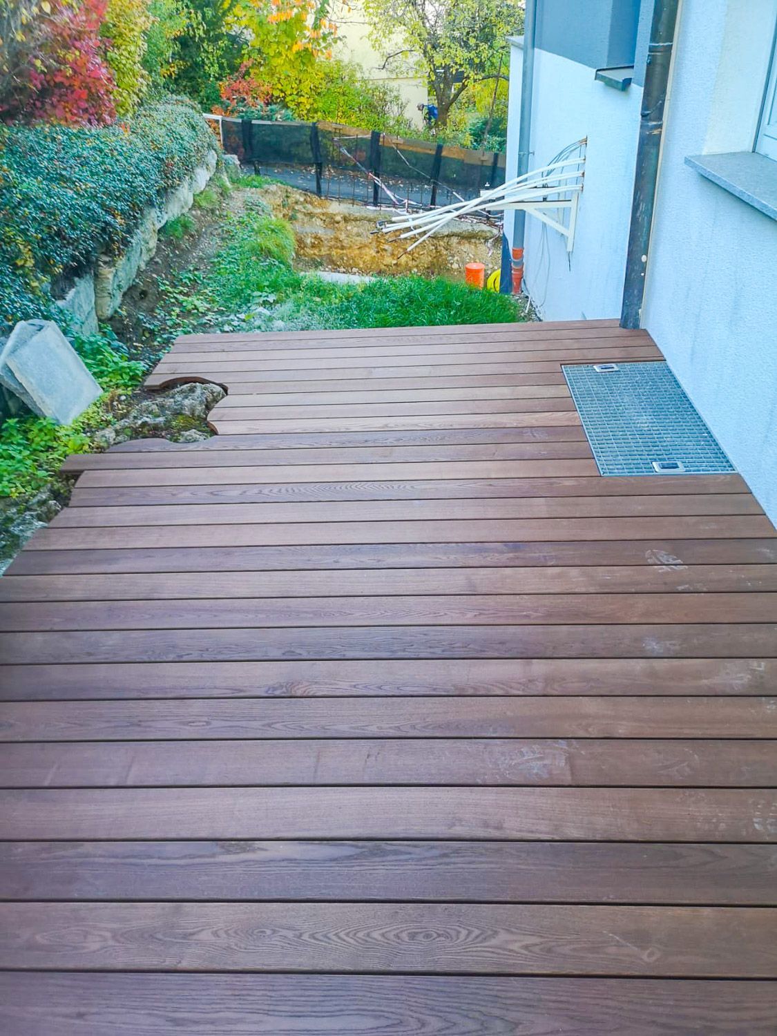 Vor einem Haus steht ein Holzdeck.