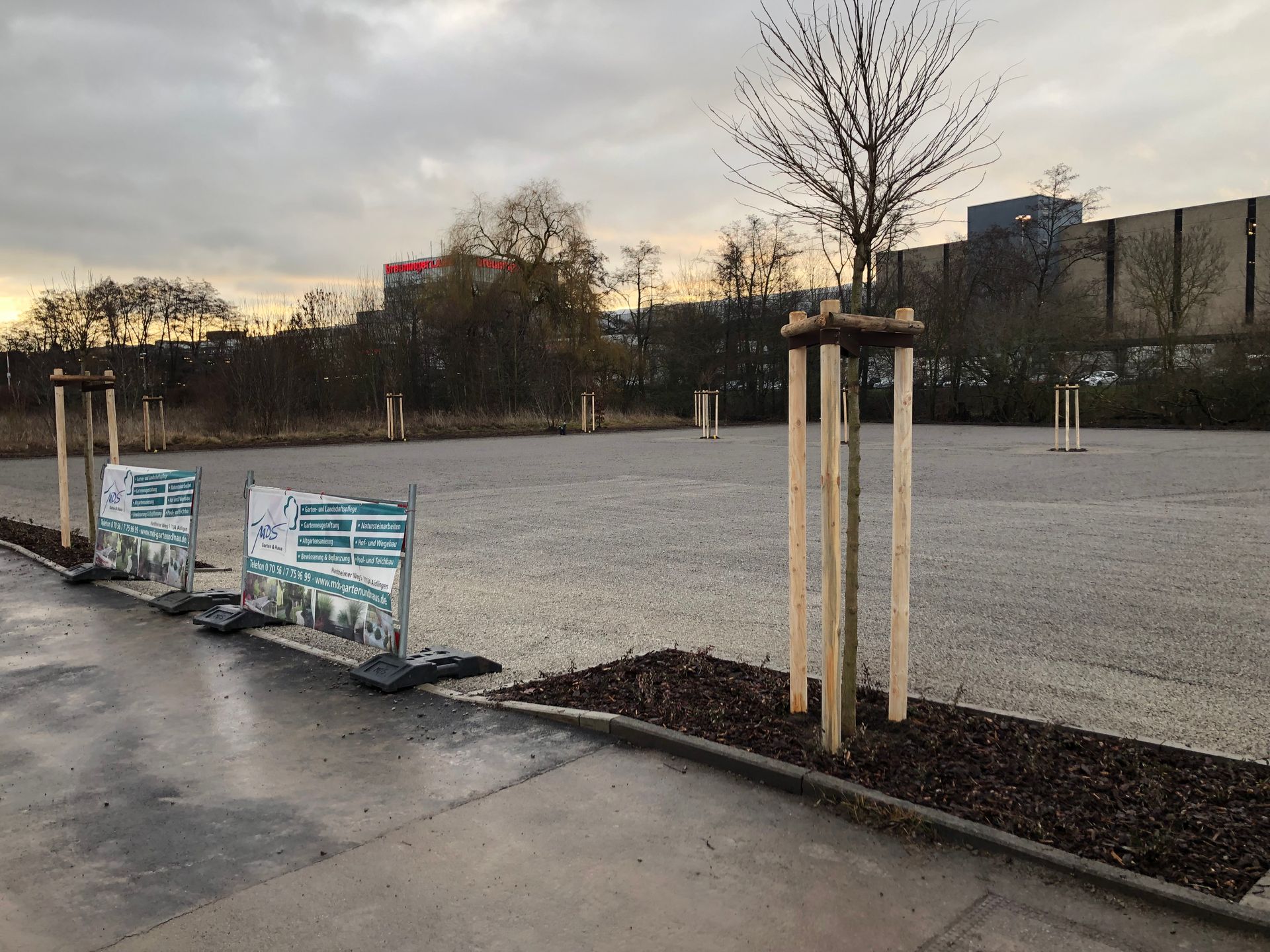 Graue Hausfassade mit Eingangstreppe, Eingang unter einem Säulengang und Pflastersteinen.