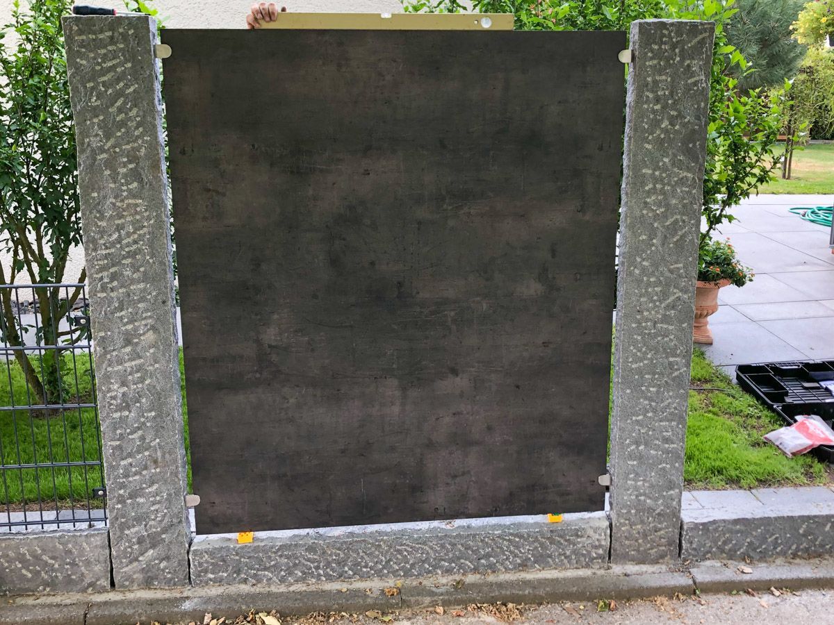 Es wird ein Zaun mit schwarzen Ziegeln gebaut.