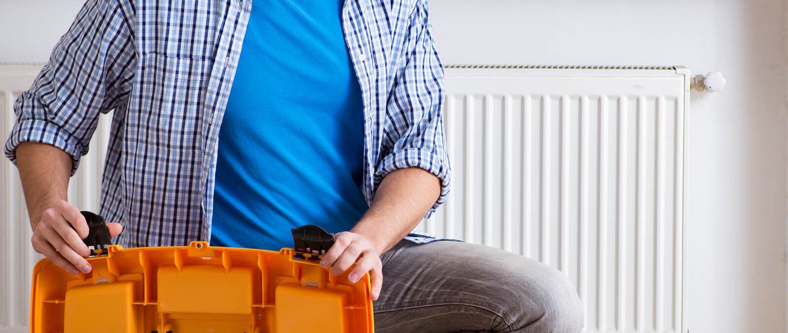 Homme avec une boite à outils devant un radiateur