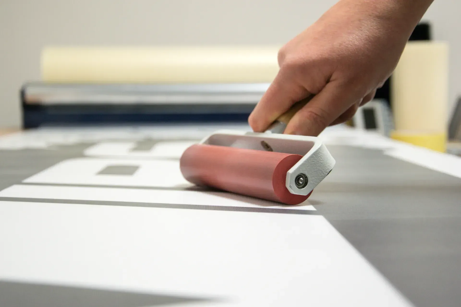 Una persona está utilizando un rodillo de goma sobre un trozo de papel.