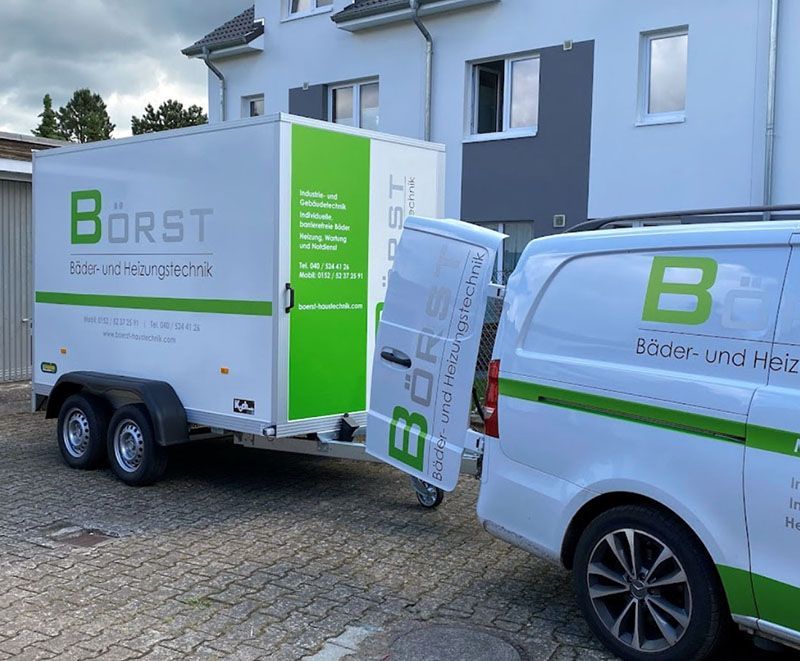 Ein grün-weißer Anhänger wird von einem weißen Lieferwagen gezogen.