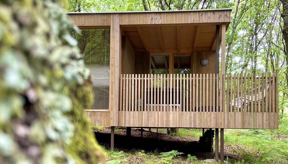 Una pequeña casa de madera con balcón en medio de un bosque.