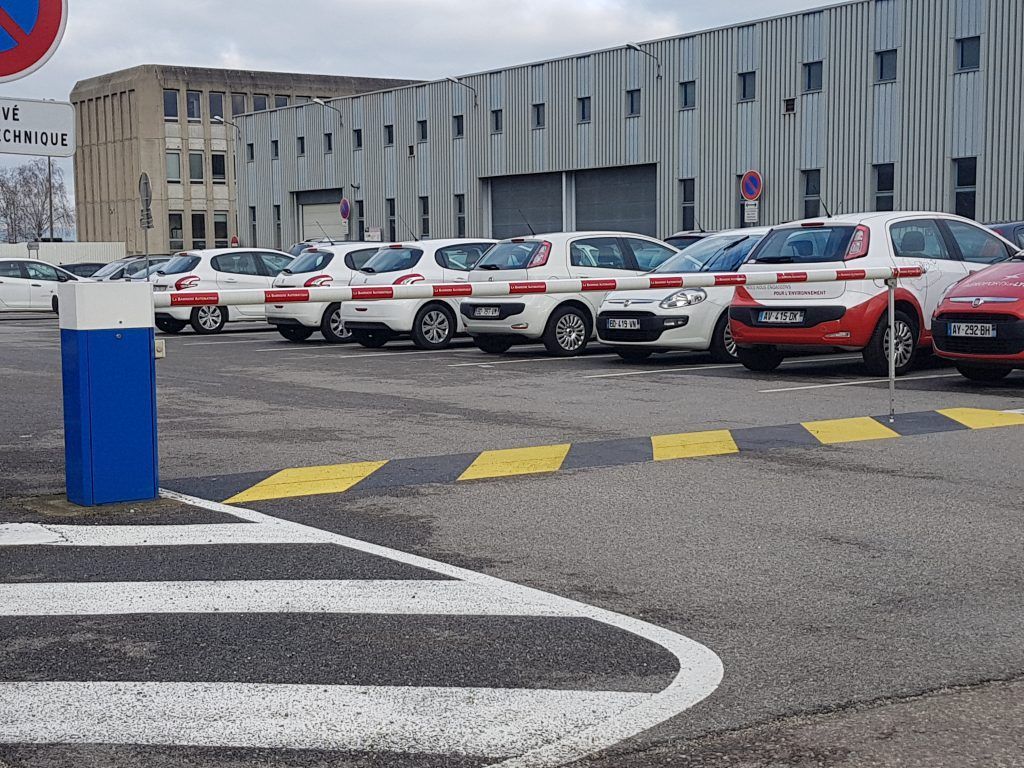 Série de voitures garées dans un parking avec une barrière