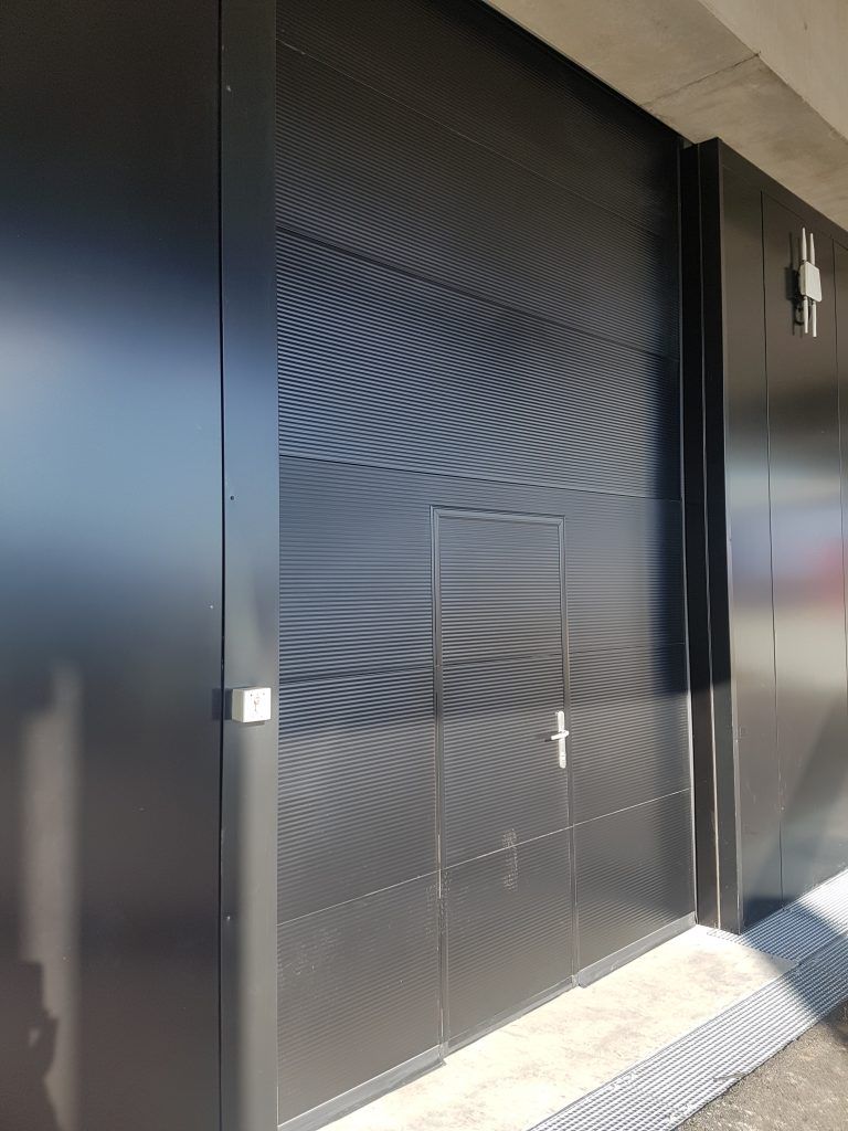 Façade métallique en alu noir avec une porte industrielle