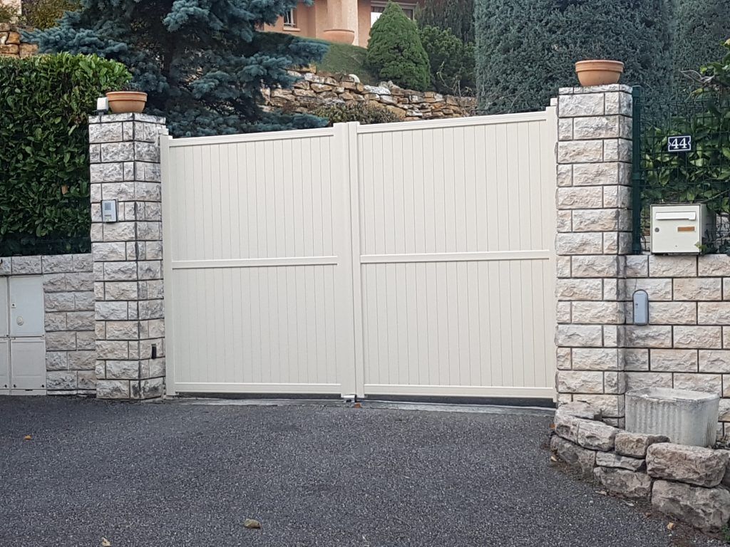 Un portail blanc et poteaux en pierres