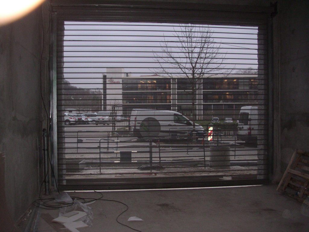 Vue sur un parking à travers un rideau métallique