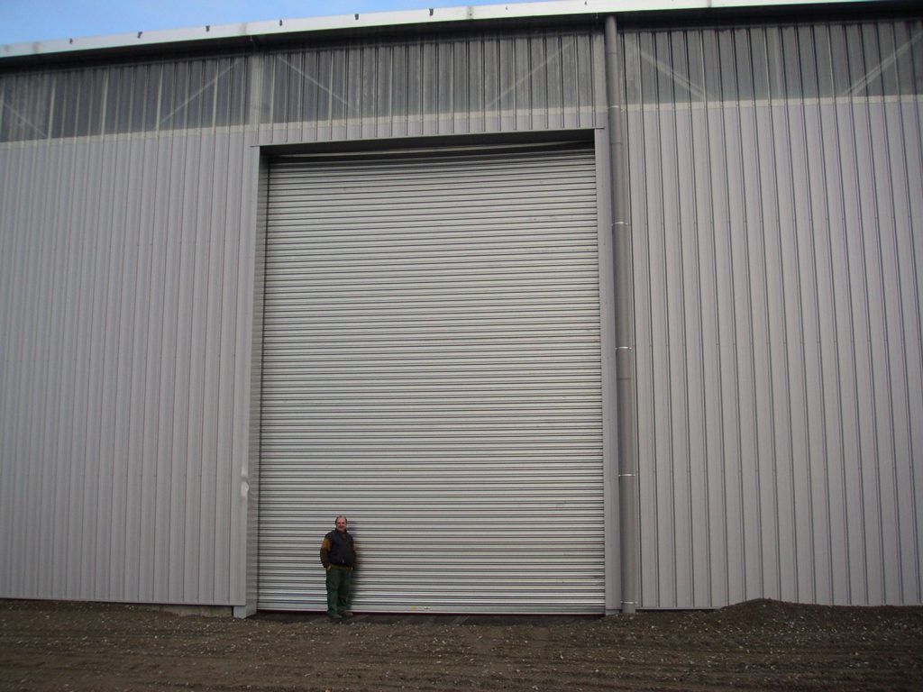 Un homme pose devant une porte industrielle