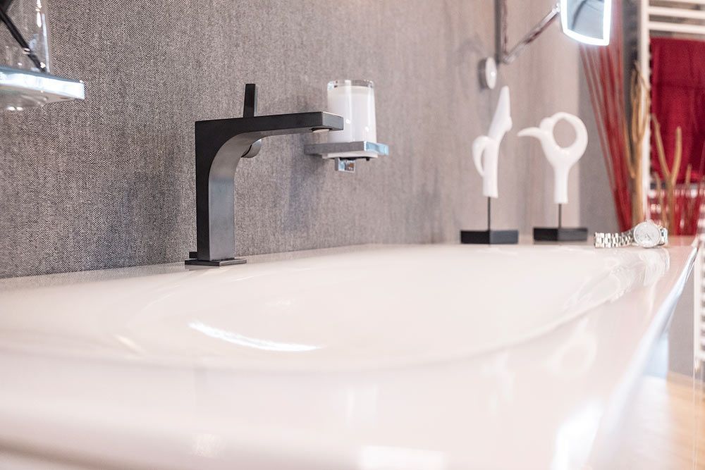 Ein Badezimmer mit einem weißen Waschbecken und einem schwarzen Wasserhahn.