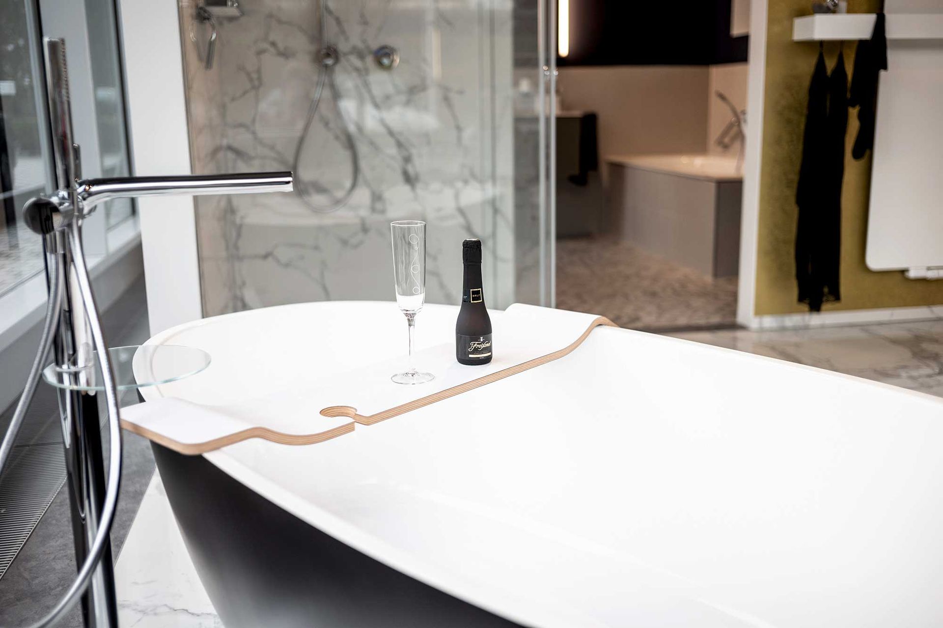 Eine Badewanne mit einer Flasche Wein und einem Glas Wein darauf.