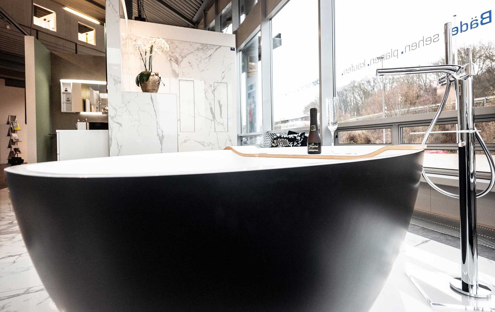 Eine schwarze Badewanne steht in einem Badezimmer neben einem Fenster.