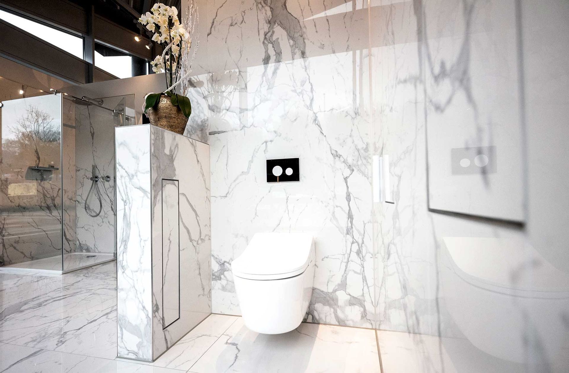 Ein Badezimmer mit Marmorwänden und einer an der Wand hängenden Toilette.