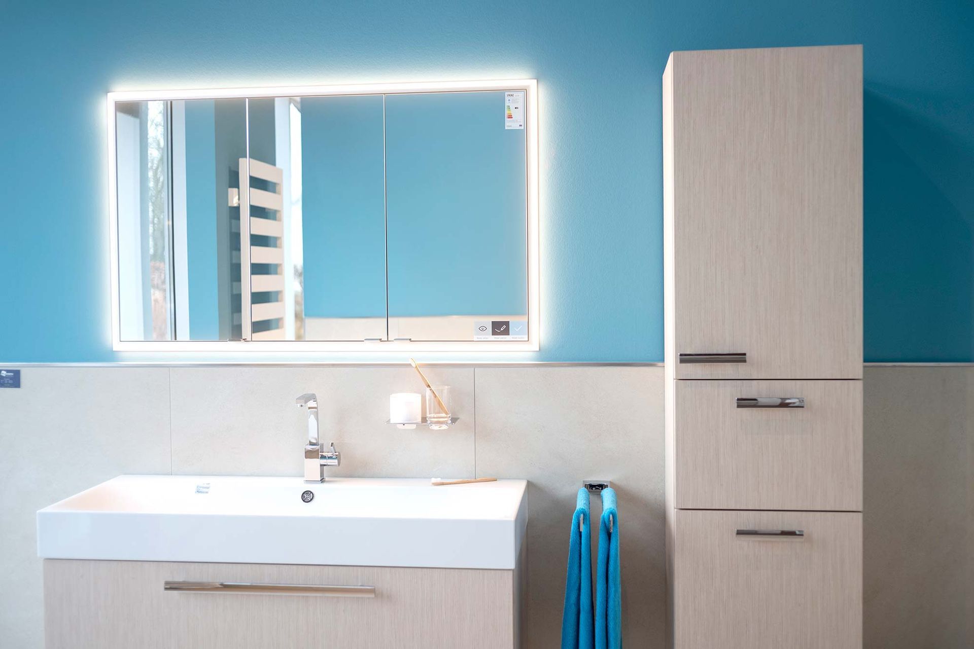 Ein Badezimmer mit Waschbecken, Spiegel und Schränken