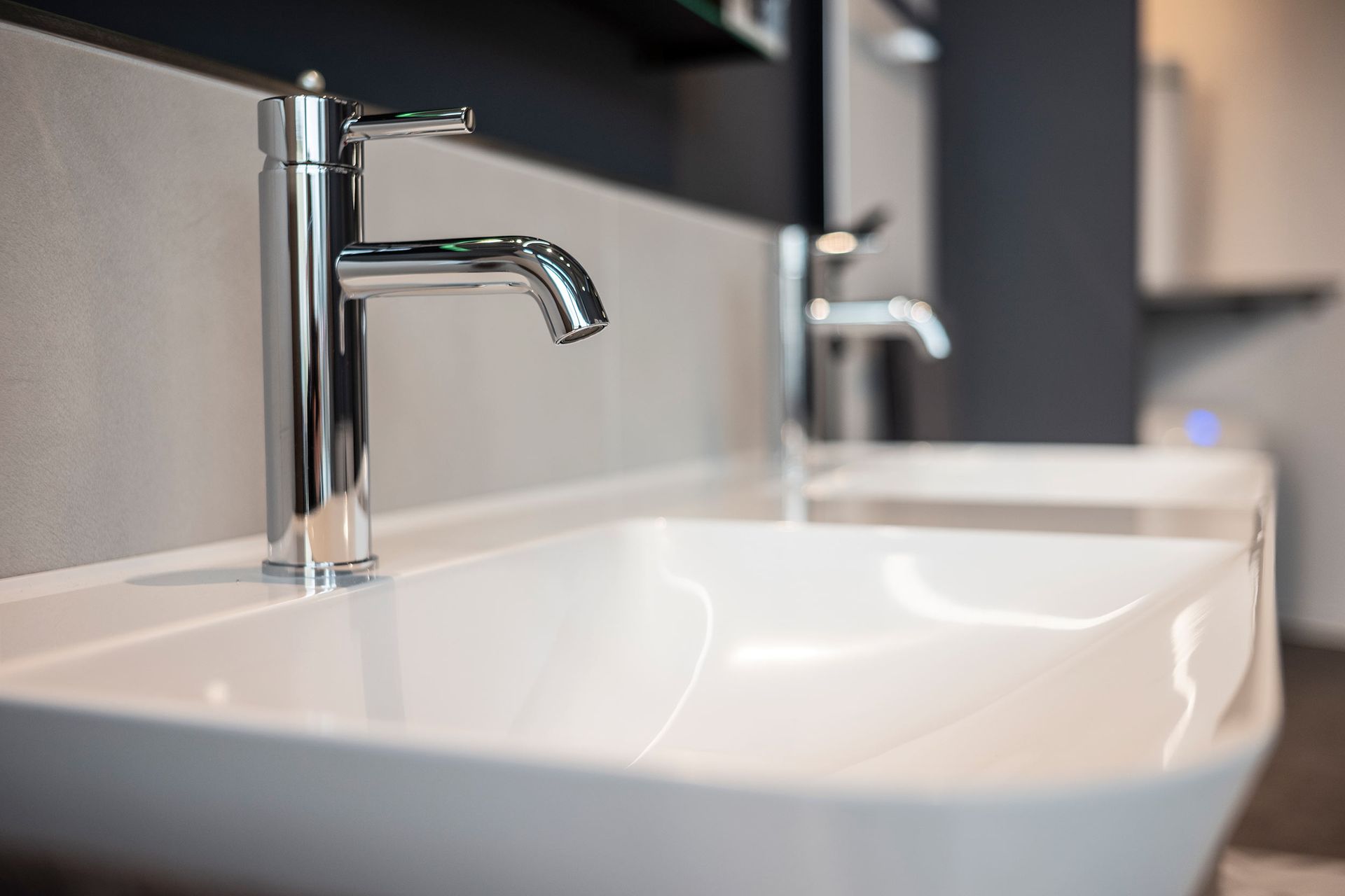 Ein Waschbecken mit zwei Wasserhähnen und einem Spiegel.