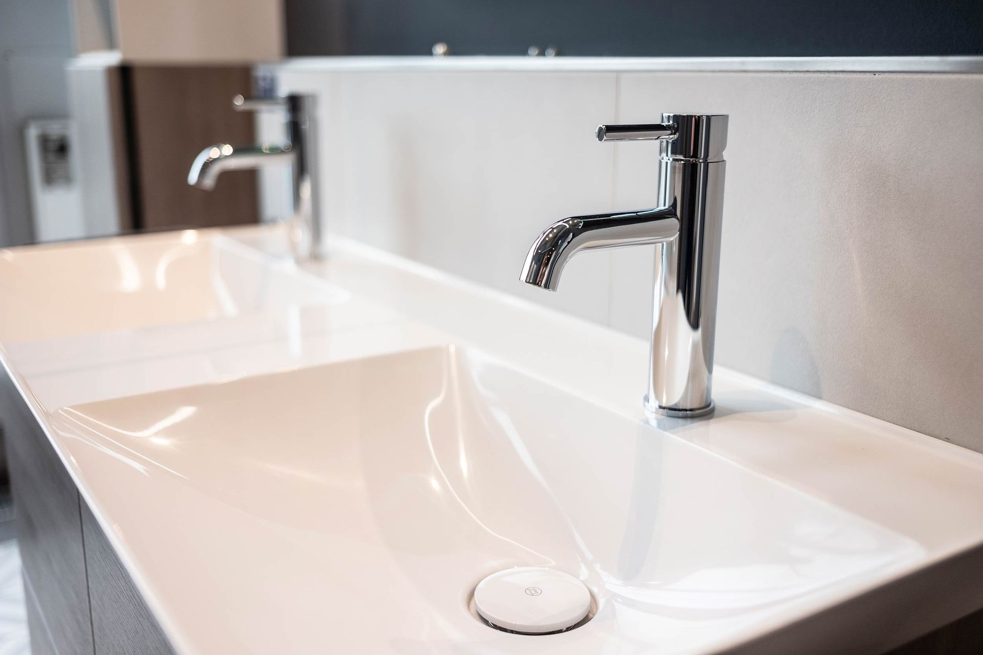 Ein Waschbecken mit zwei Wasserhähnen und einem Spiegel.