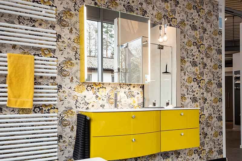 Ein Badezimmer mit gelben Schränken, einem Waschbecken, einem Spiegel und einem Handtuchhalter.