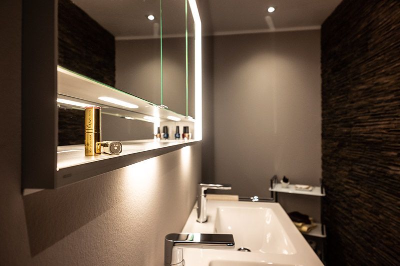 Ein Badezimmer mit Waschbecken, Spiegel und Regal