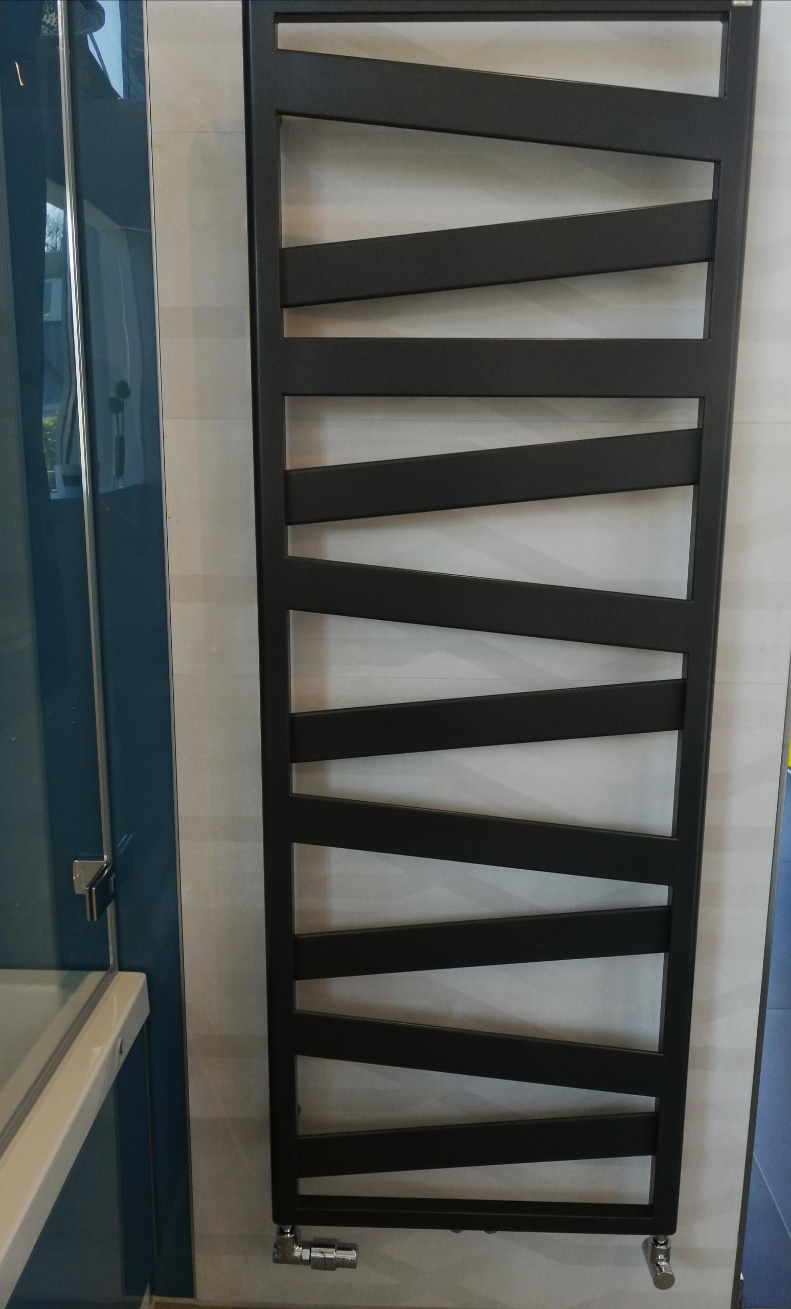 Ein schwarzer Handtuchhalter hängt an einer weißen Wand in einem Badezimmer.