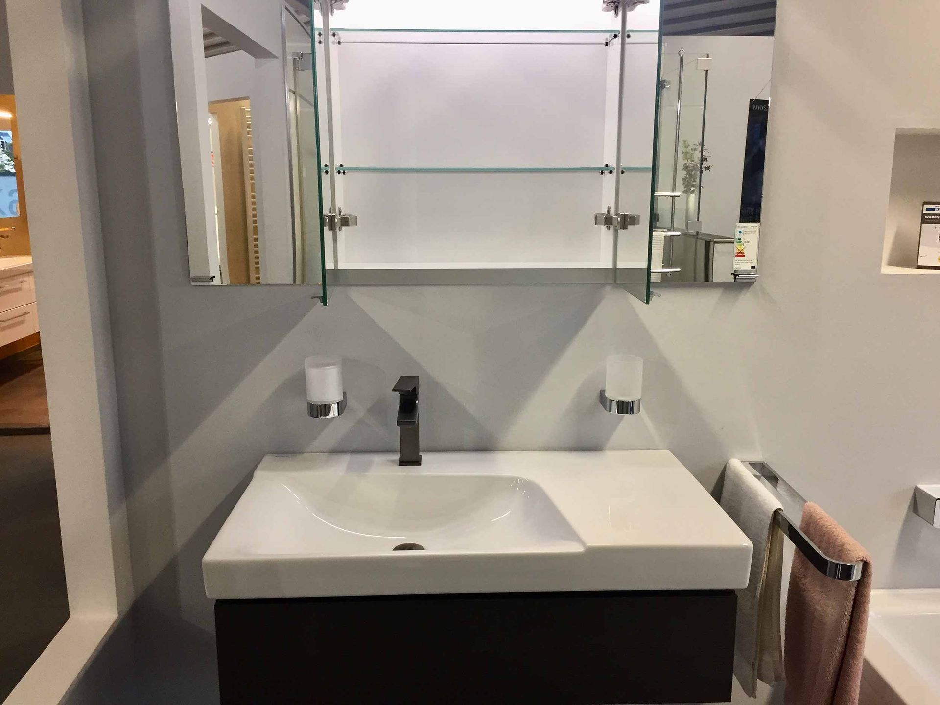 Ein Badezimmer mit Waschbecken, Spiegel und Handtuchhalter