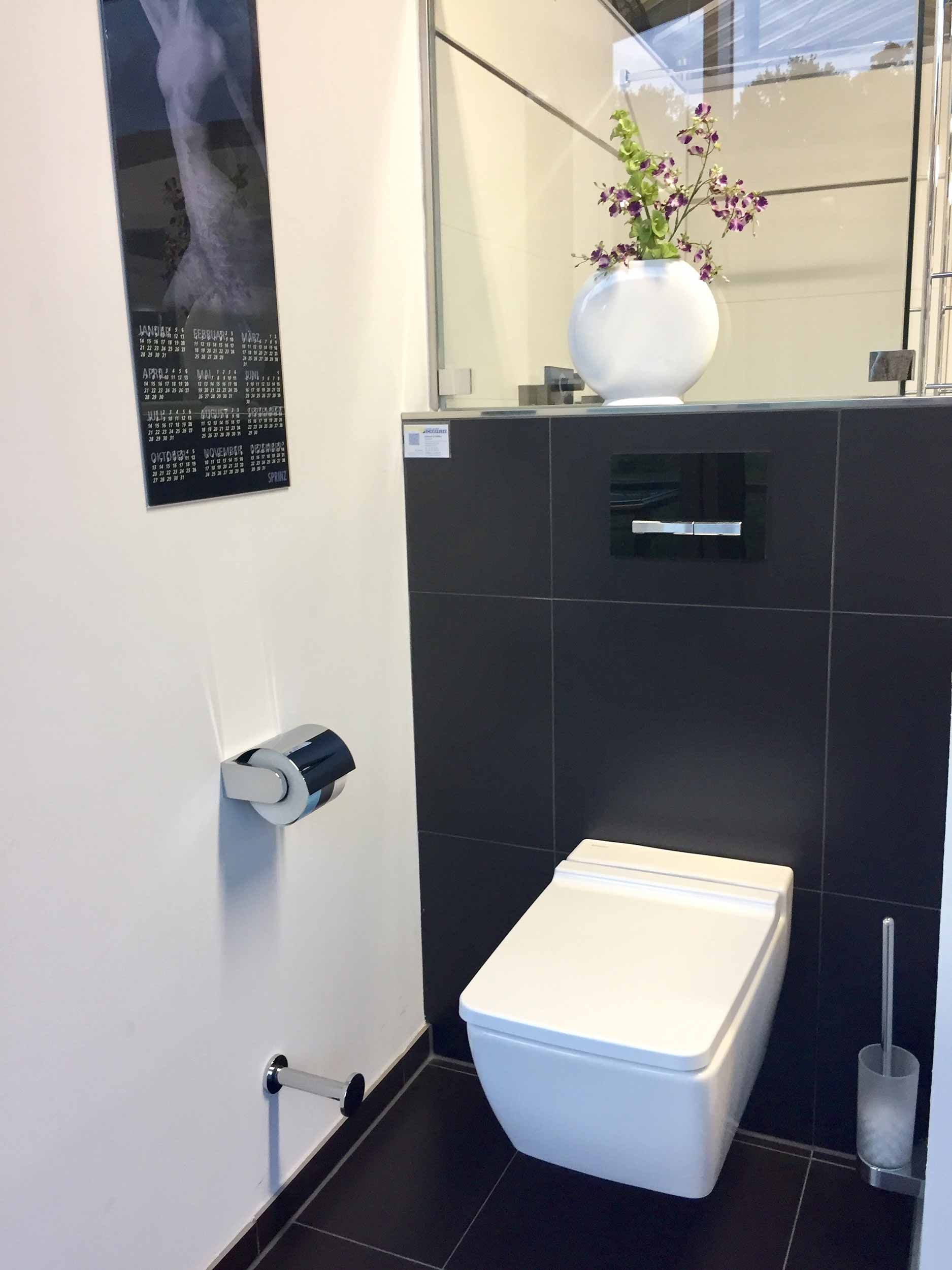 Ein Badezimmer mit Toilette und einer Blumenvase