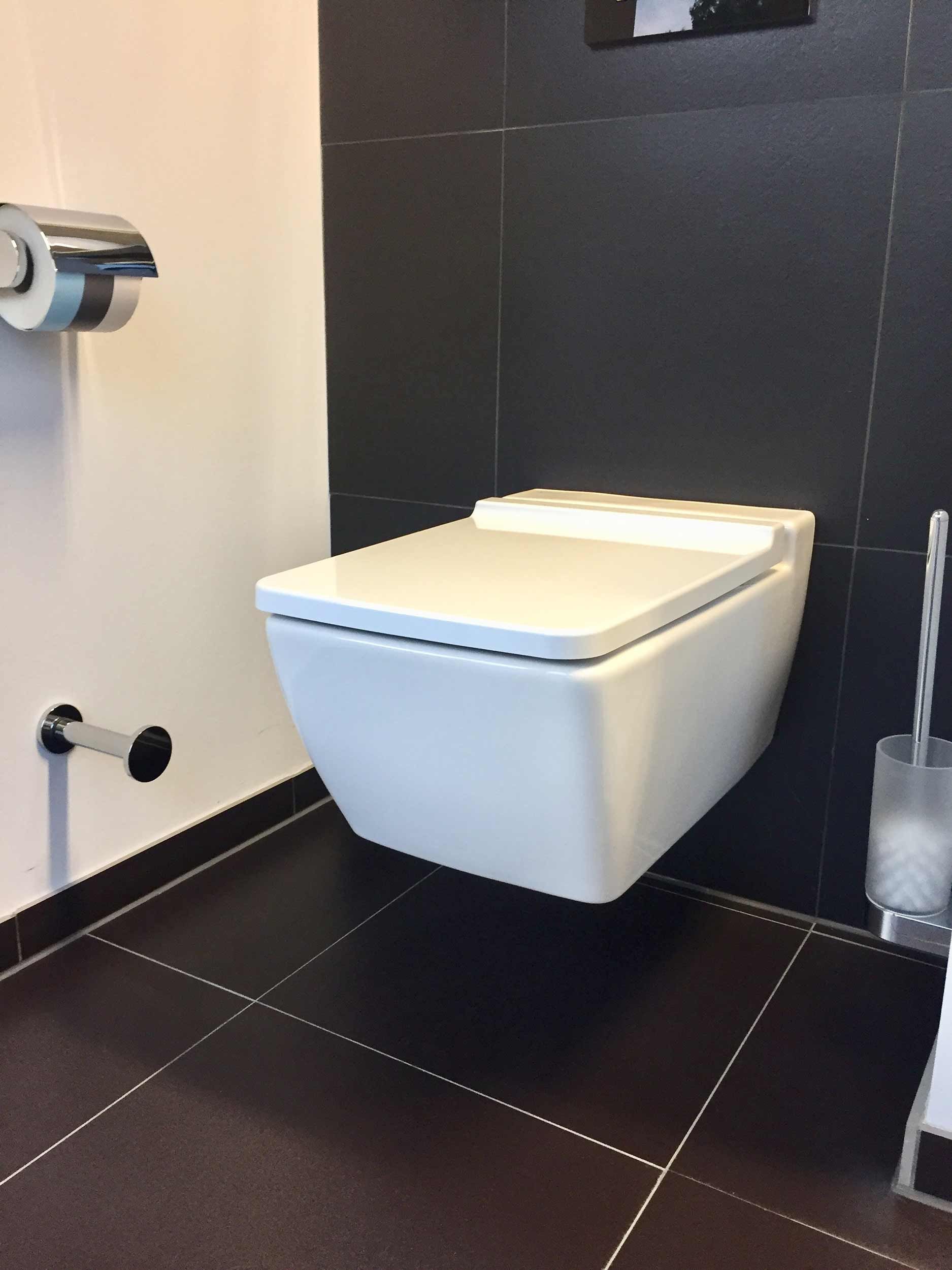 Eine weiße Toilette hängt an der Wand in einem Badezimmer