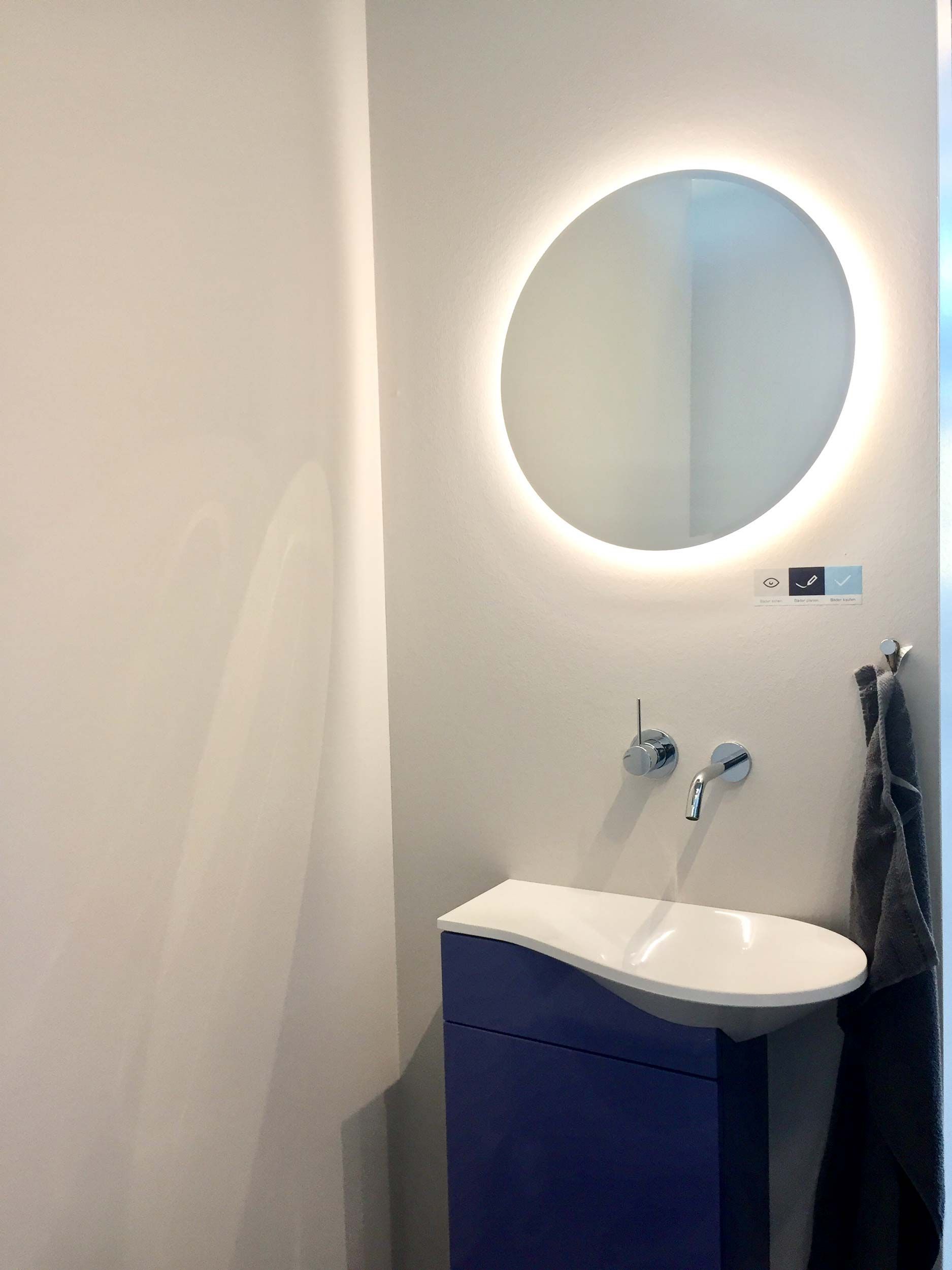 Ein Badezimmer mit Waschbecken und rundem Spiegel