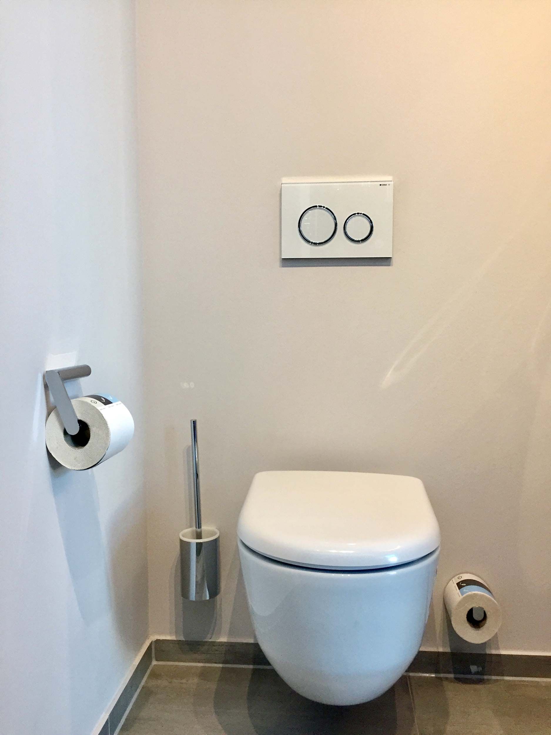 In einem Badezimmer hängt eine weiße Toilette an der Wand.