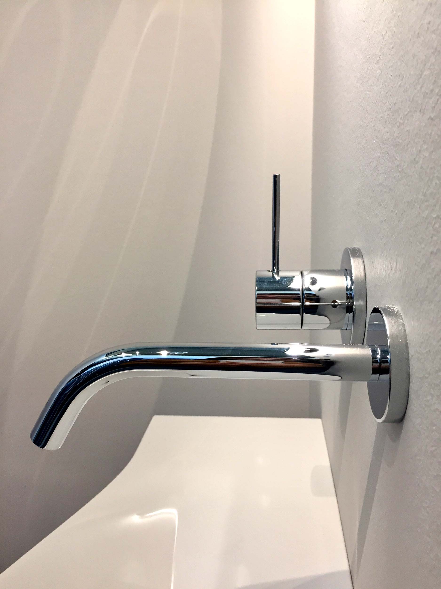 Ein Waschbecken mit einem Chromhahn an der Wand