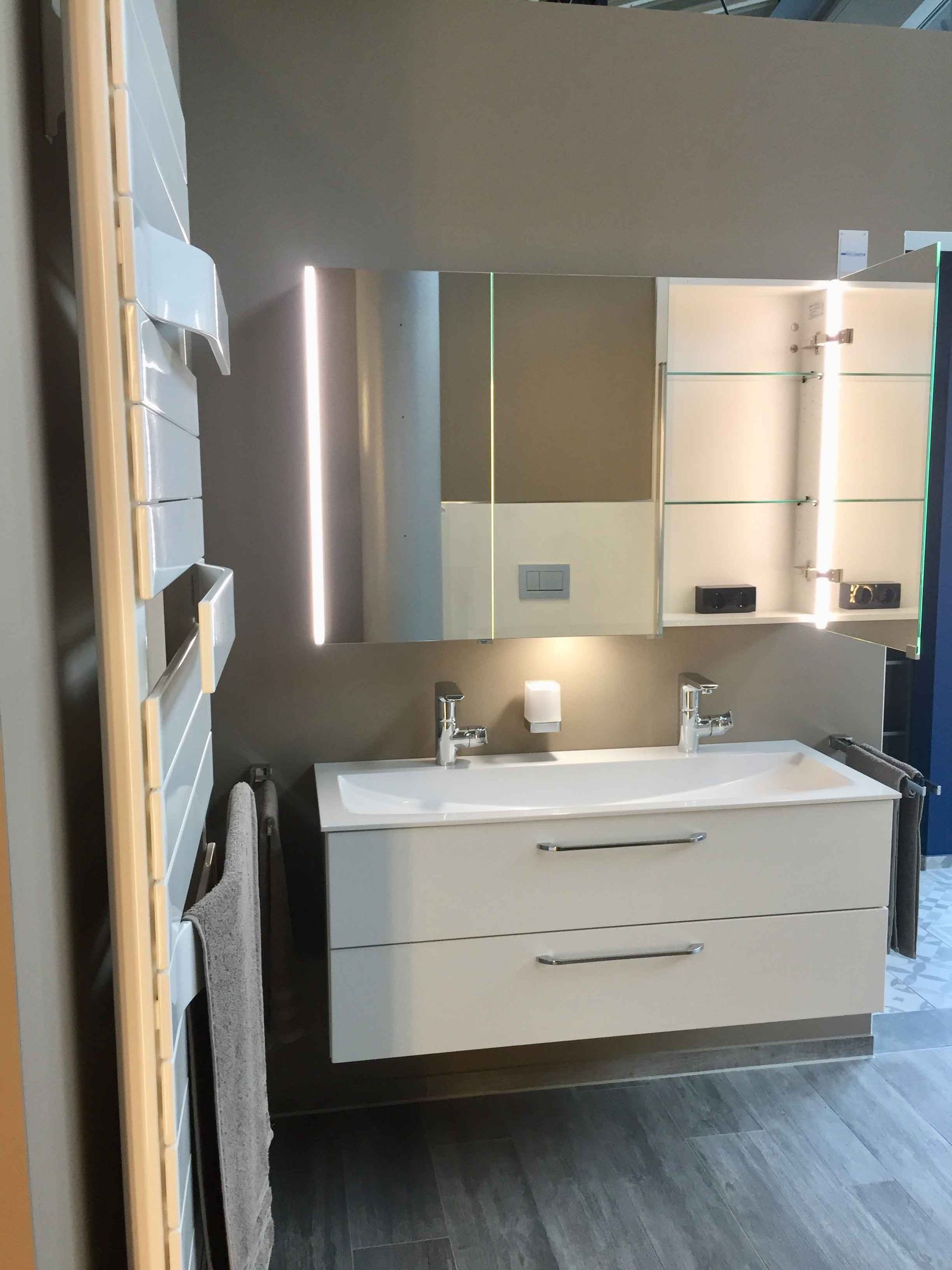 Ein Badezimmer mit Waschbecken, Spiegel und Schränken