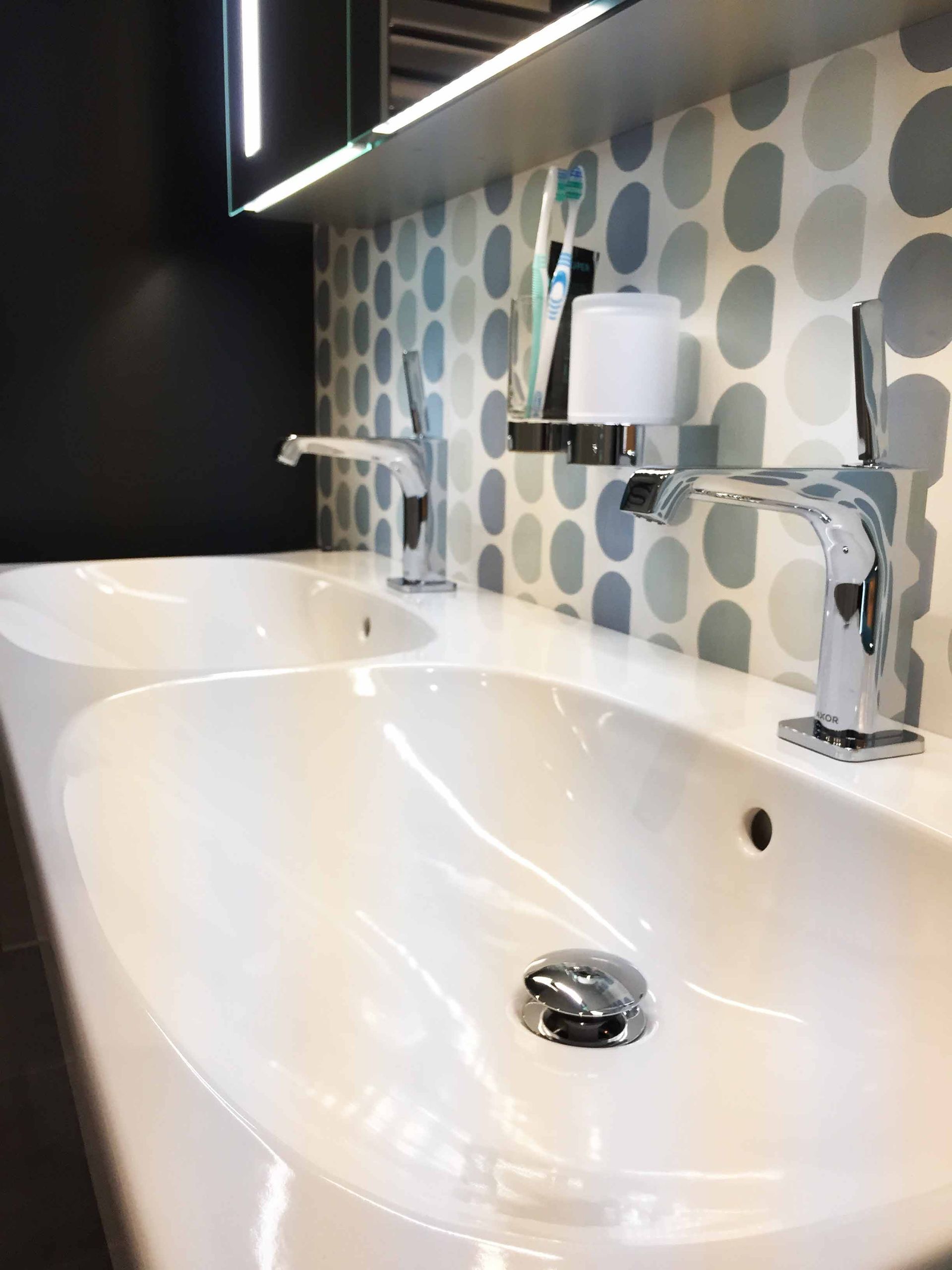 Ein Badezimmer mit zwei Waschbecken und einer gepunkteten Wand