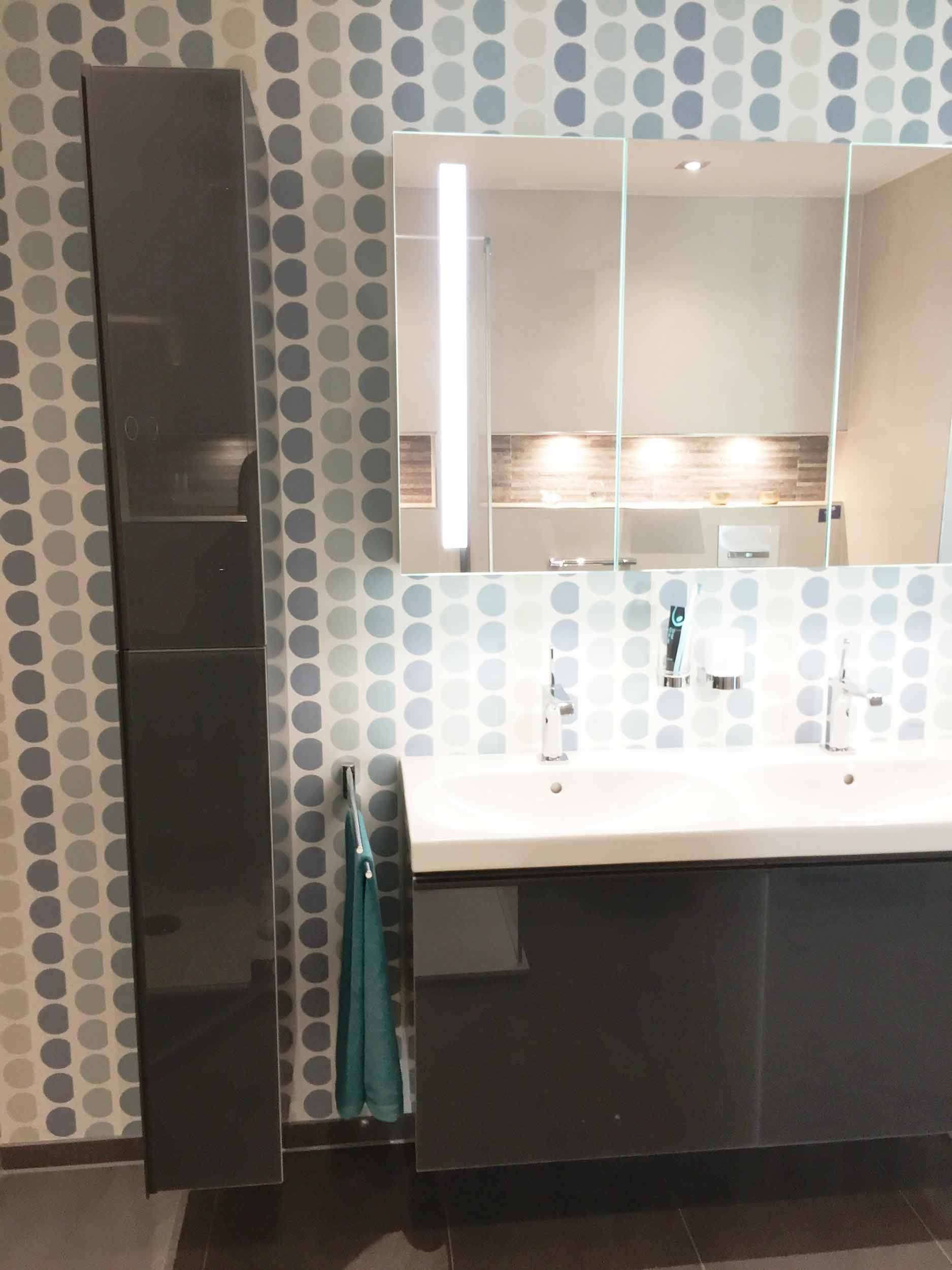 Ein Badezimmer mit Waschbecken, Spiegel und Hochschrank