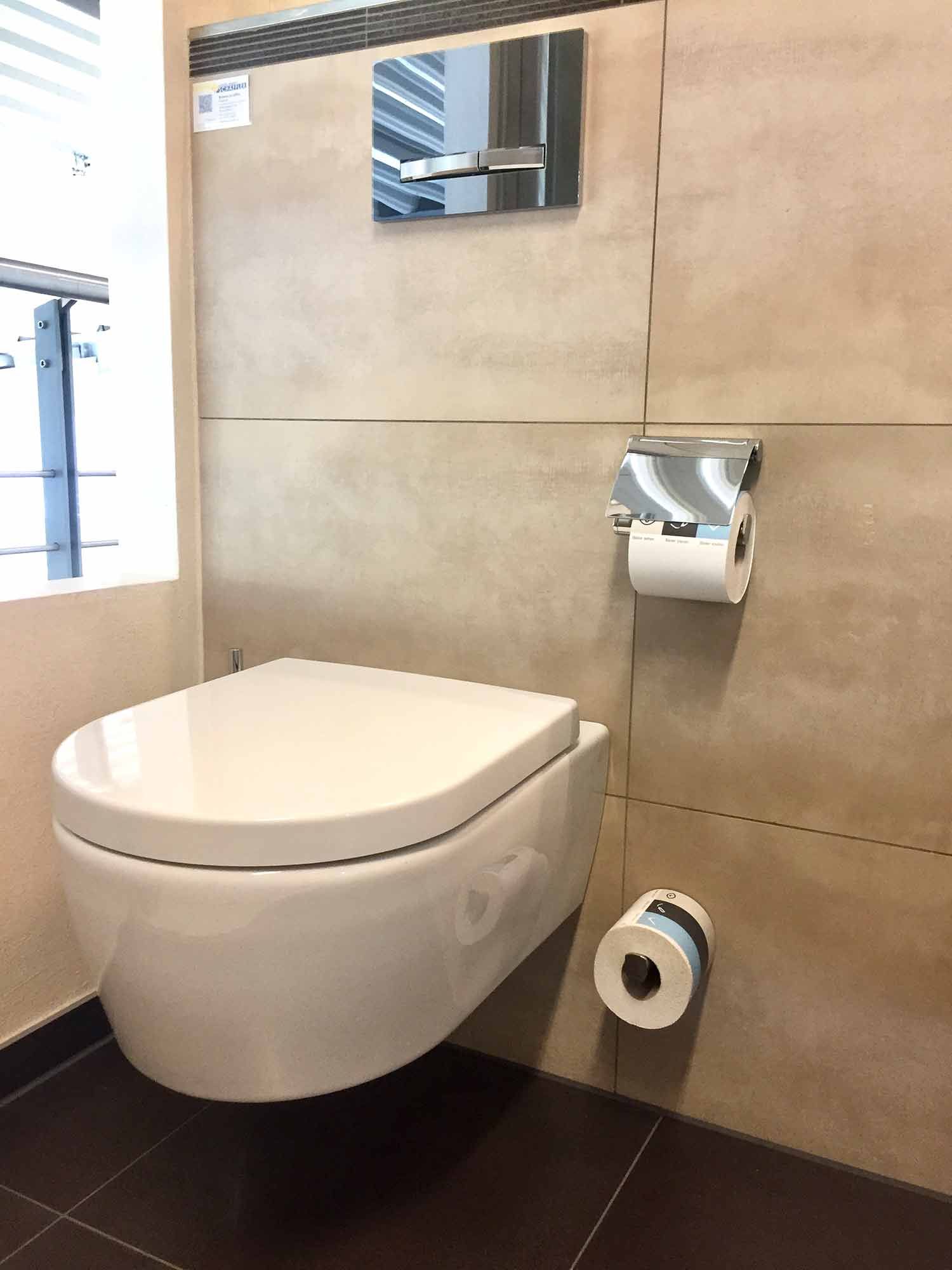 In einem Badezimmer ist eine weiße Toilette an der Wand montiert.