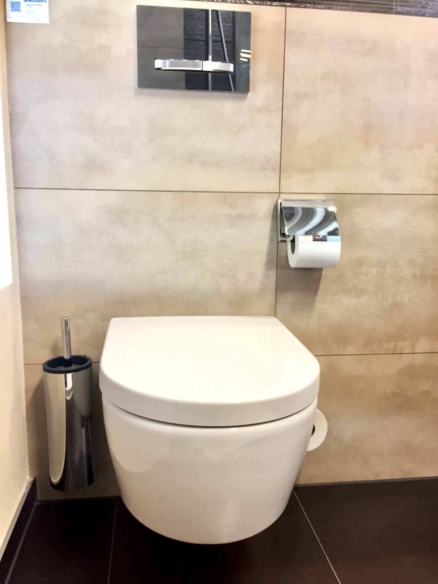 In einem Badezimmer ist eine weiße Toilette an der Wand montiert.