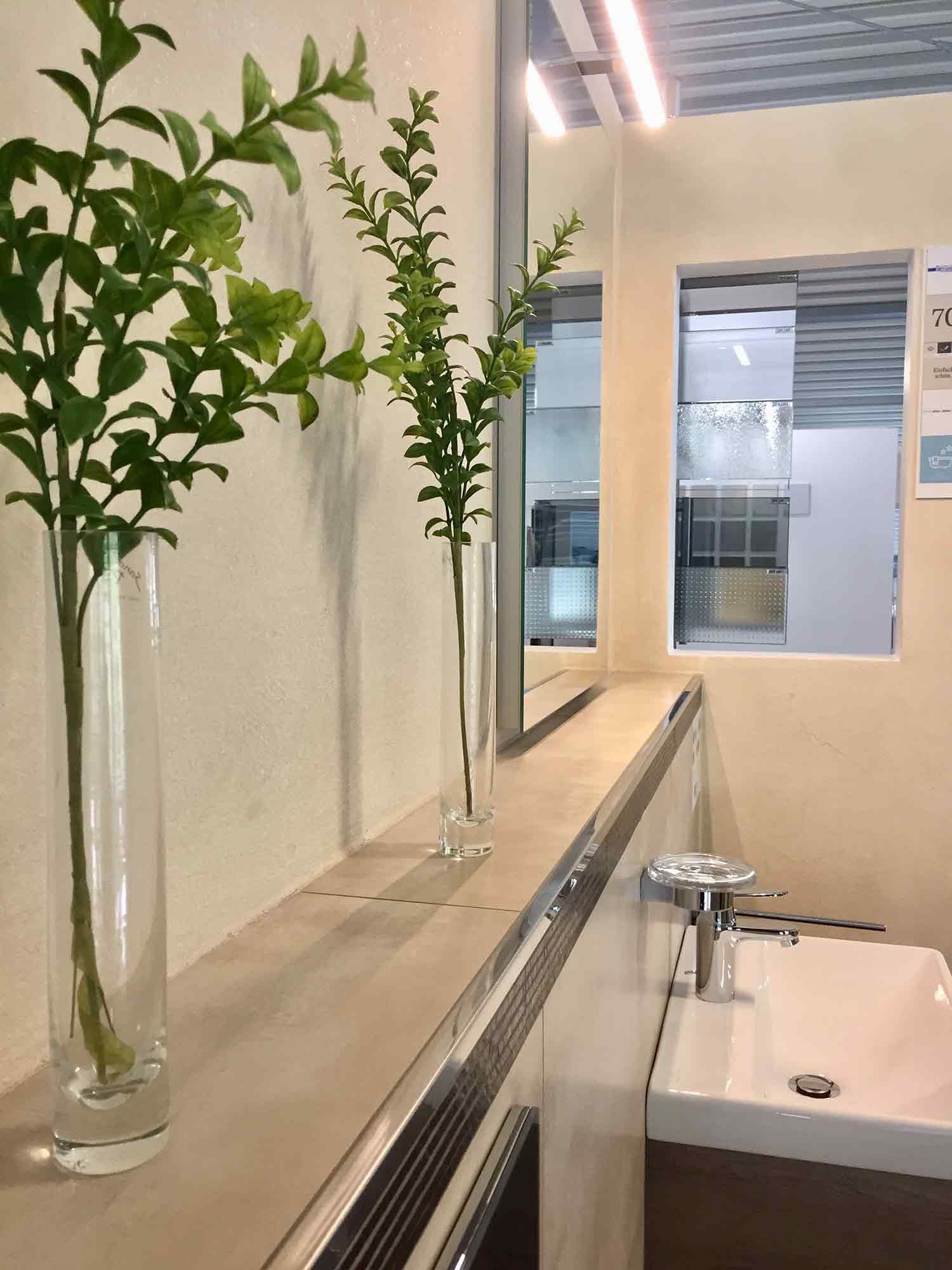 Ein Badezimmer mit Waschbecken und Spiegel und Pflanzen in Vasen