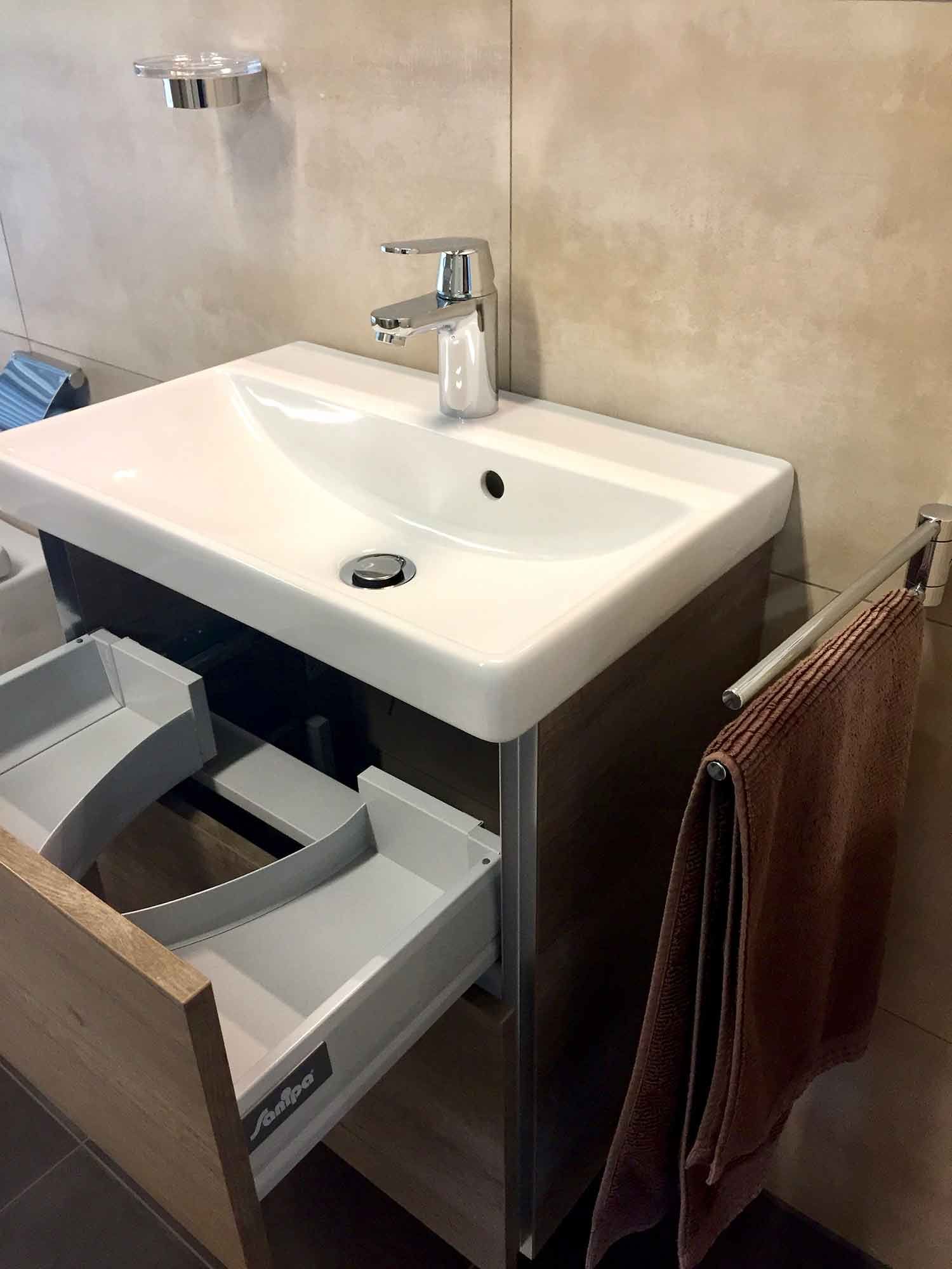 Ein Waschbecken im Badezimmer mit offenen Schubladen und einem Handtuch, das an der Wand hängt