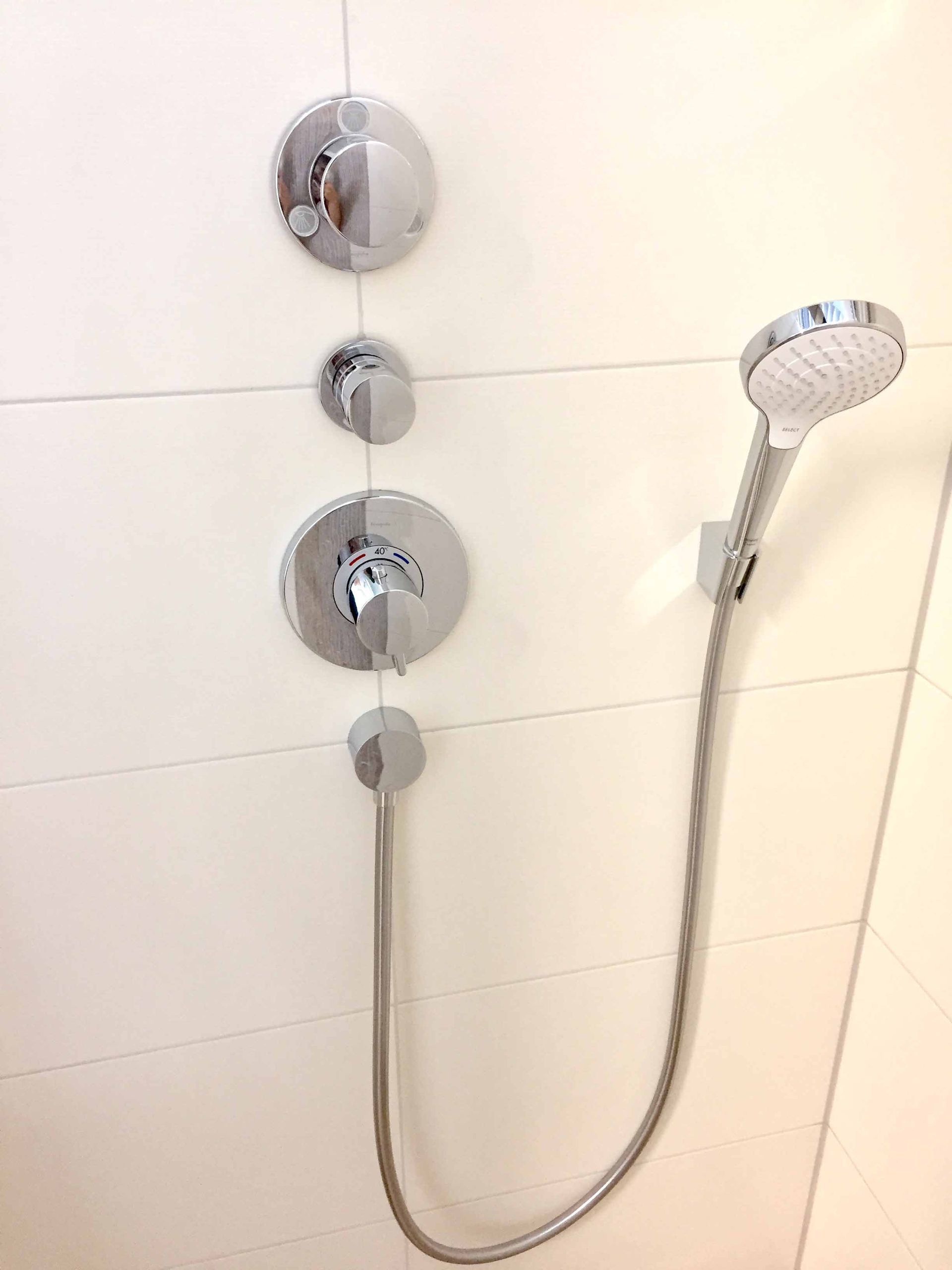 In einem Badezimmer ist ein Duschkopf an einen Schlauch angeschlossen.