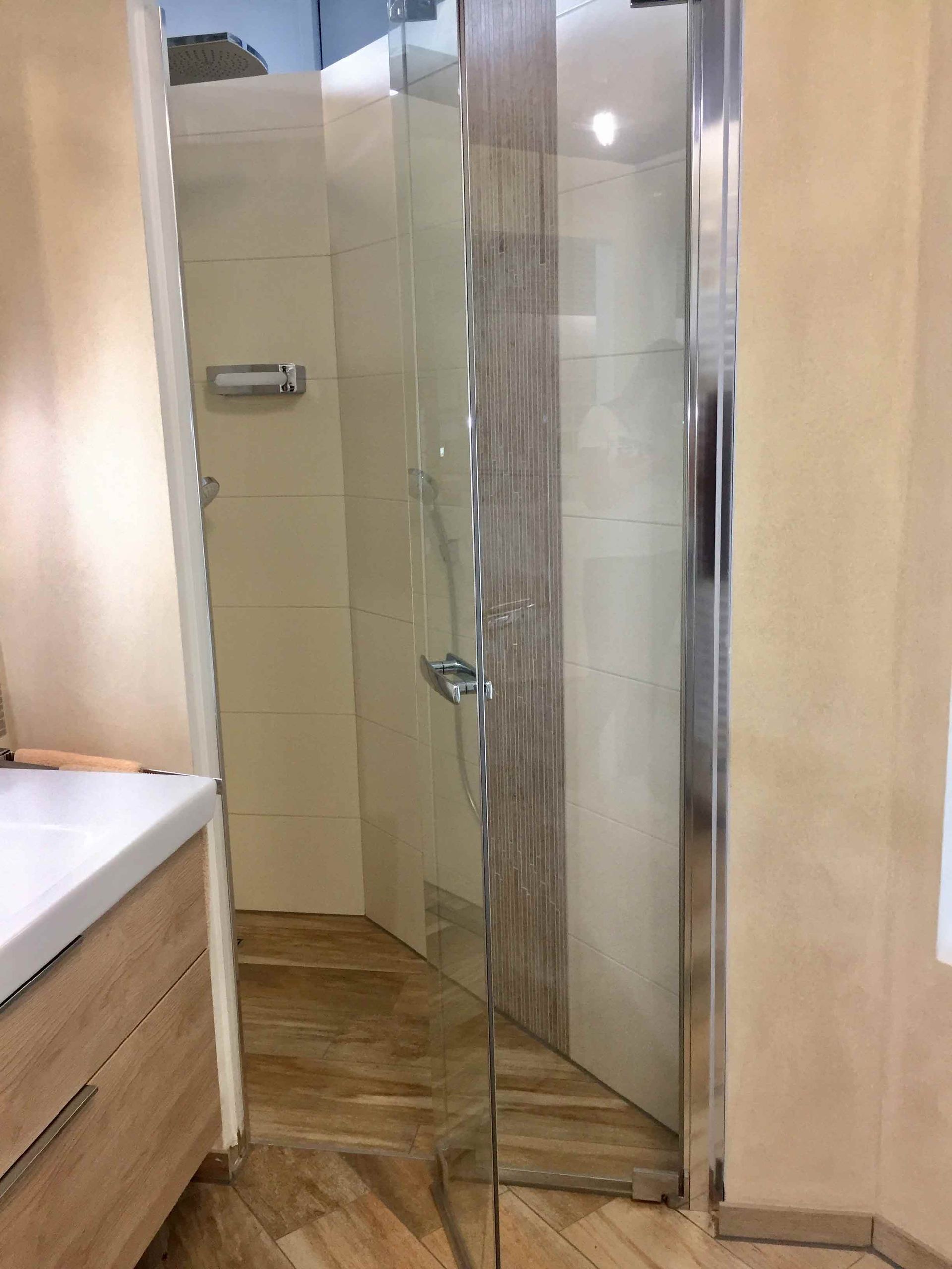 Ein Badezimmer mit ebenerdiger Dusche und Waschbecken.