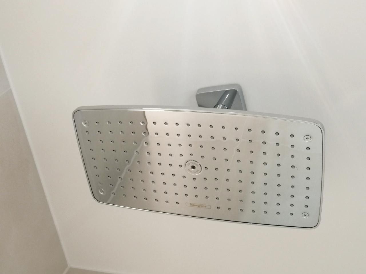 Ein Duschkopf hängt an einer weißen Wand