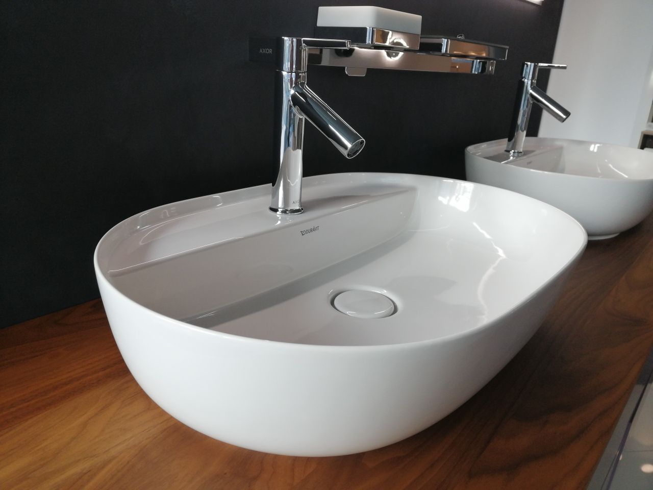 Zwei weiße Waschbecken stehen auf einer Holztheke